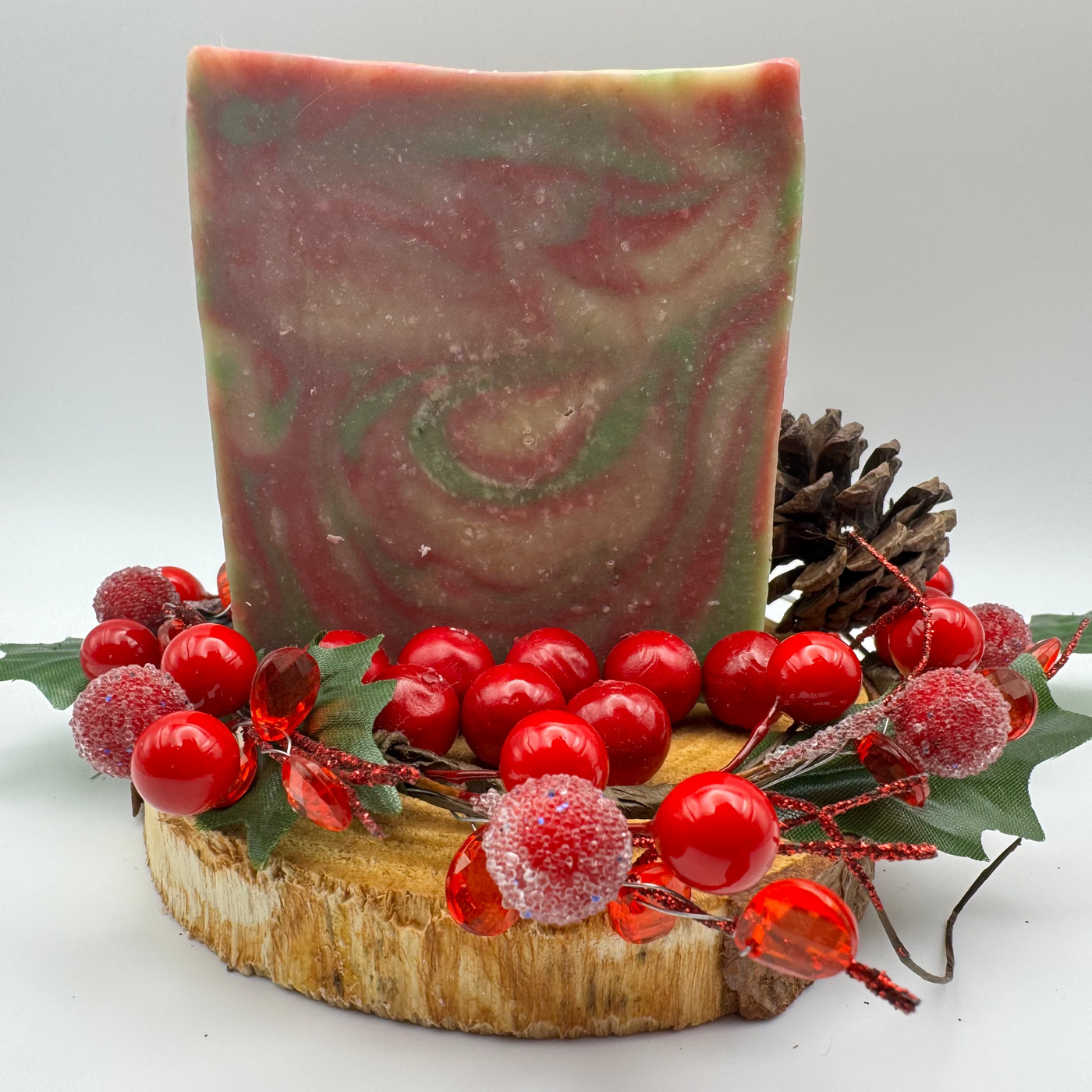 Decorative soap with red berries and a pine cone on a white background