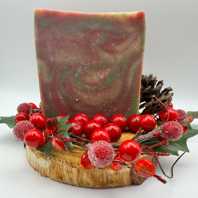 Decorative soap with red berries and a pine cone on a white background