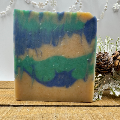 Colorful soap bar with green and blue layers on a wooden surface with decorative elements.